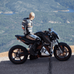 Man sitting on a motorcycle overlooking the water