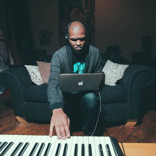 stirling toles working a keyboard and laptop on a navy blue couch