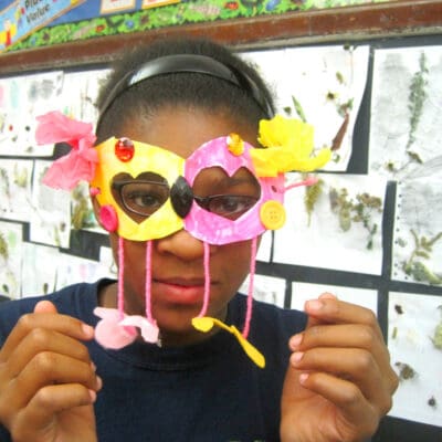 student holding a pink and yellow mask created in a CAP class