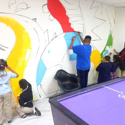 Students and instructor working on a soccer ball mural