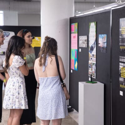 people reviewing work pinned on a moving wall at the Student Exhibition Opening