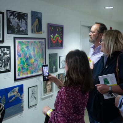 People looking at work displayed on a wall at the student exhibition opening