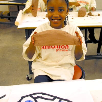 A student holds up a clay car sculpture in the CAP program