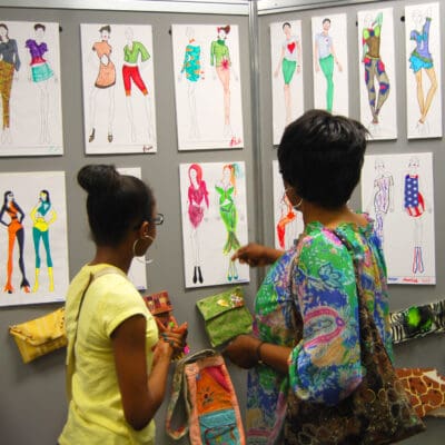 A student and family member review fashion illustrations created in CAP