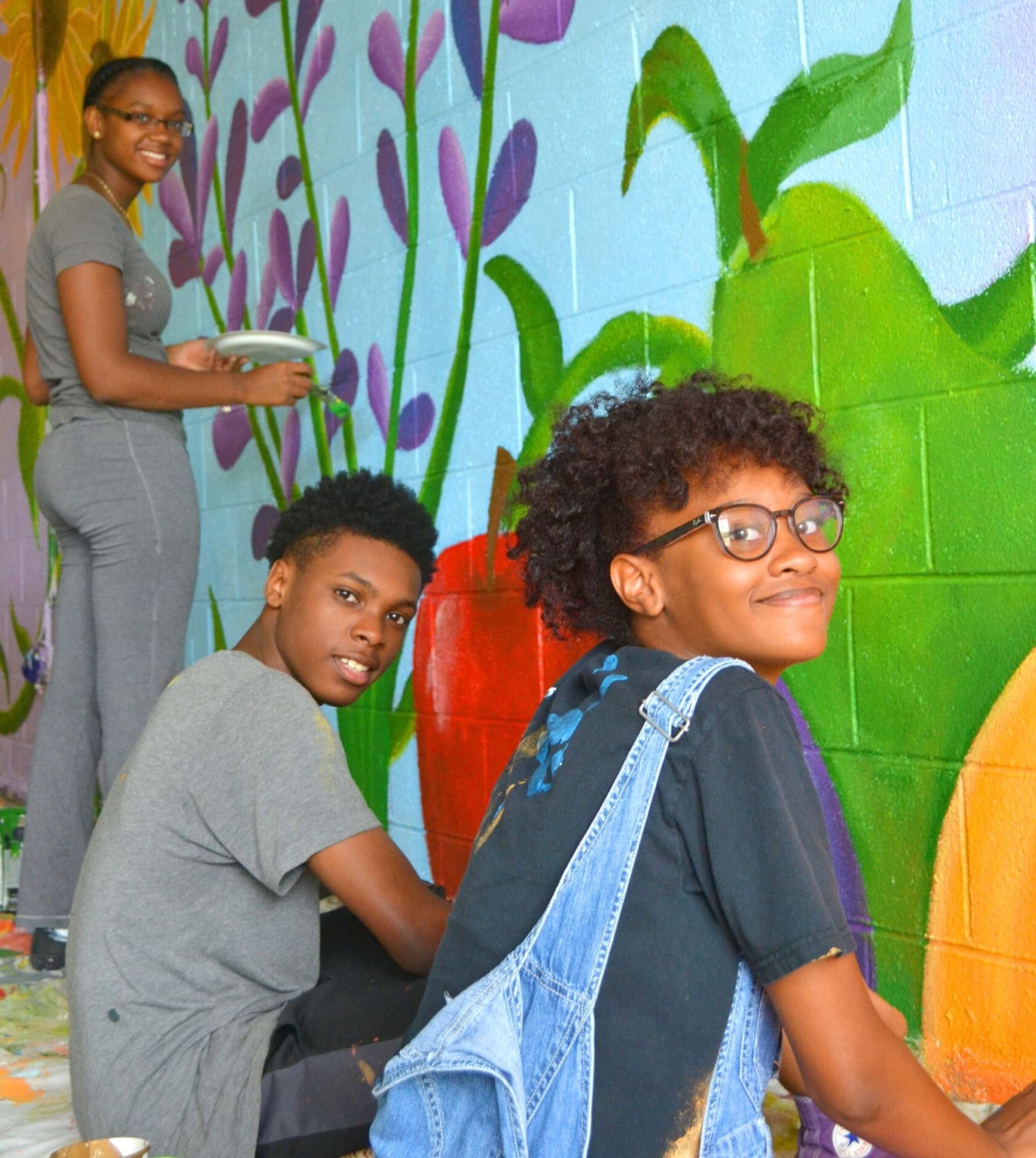 students work on a mural of flowers and fruit as part of a CAP class