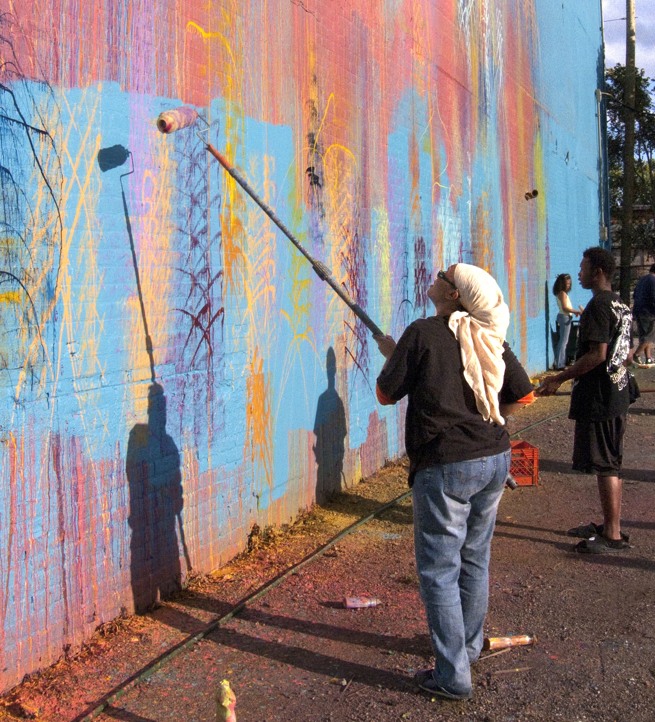 people painting a rainbow wall mural