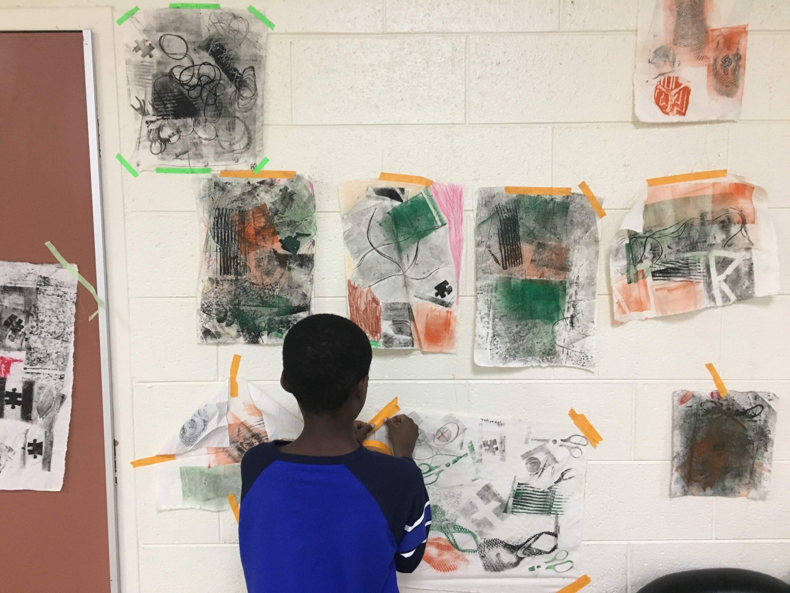 student taping artwork to the wall