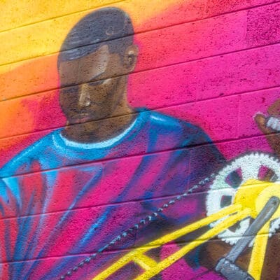 pink, yellow and red mural of a man and a bike
