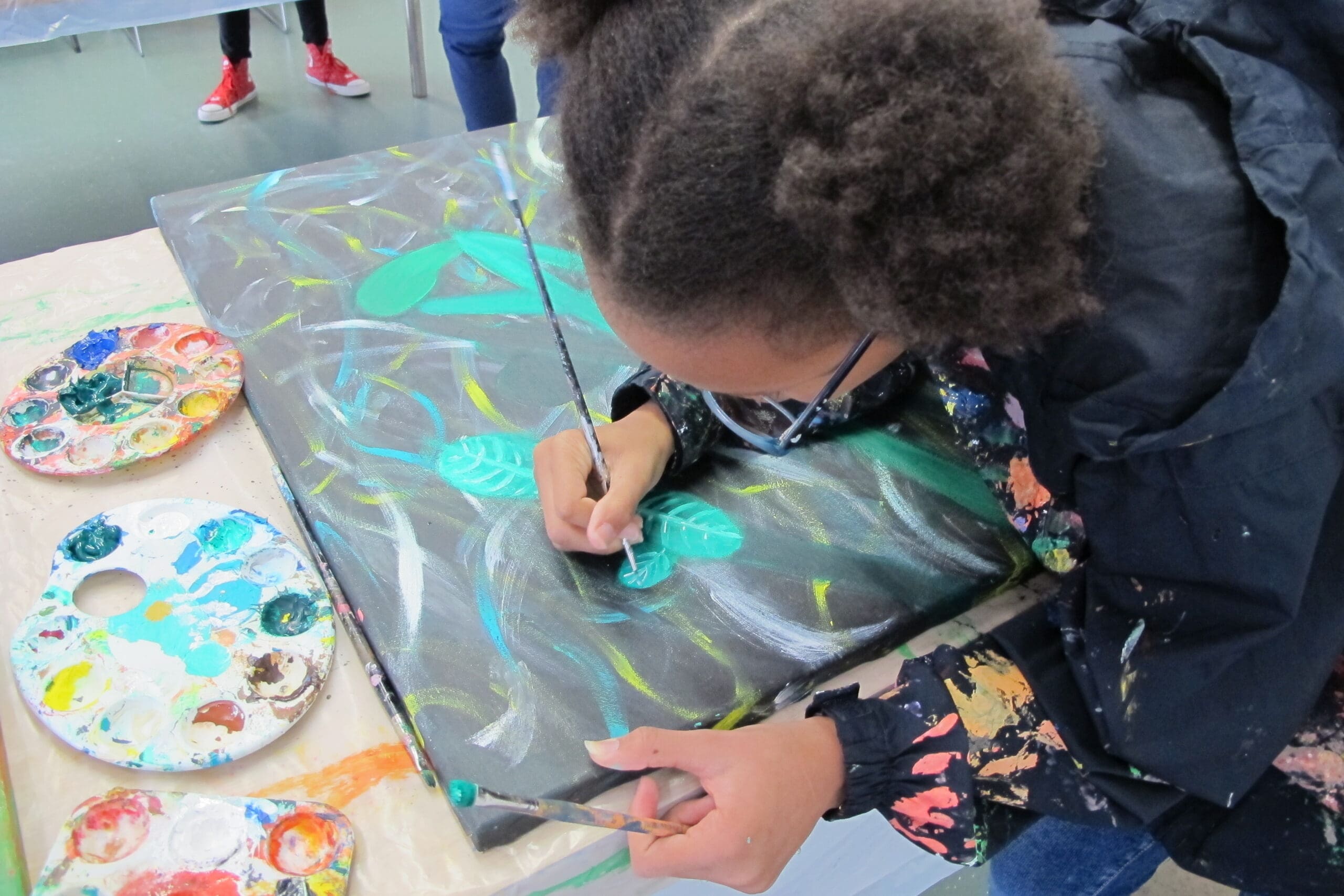 student painting a black, turquoise and white painting