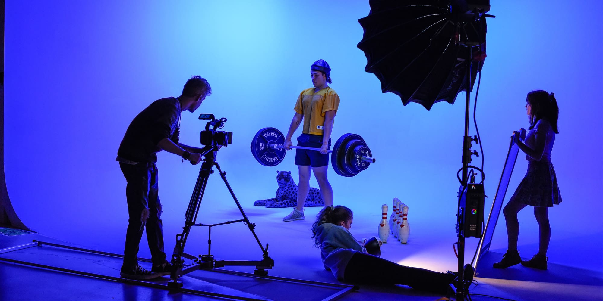 students filming a weight lifter in a dark room