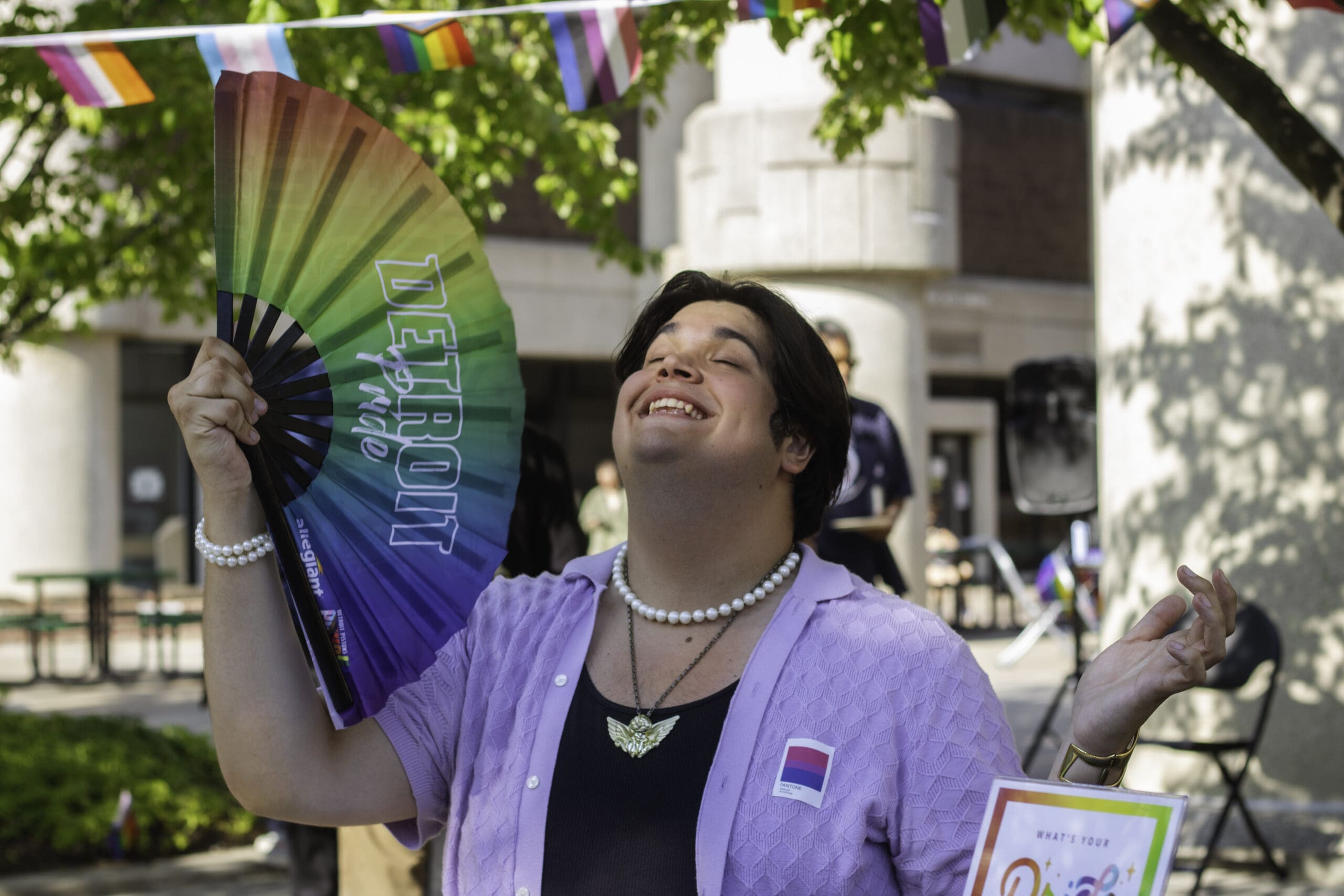 Person joyously fans themselves with Detroit PRIDE fan.