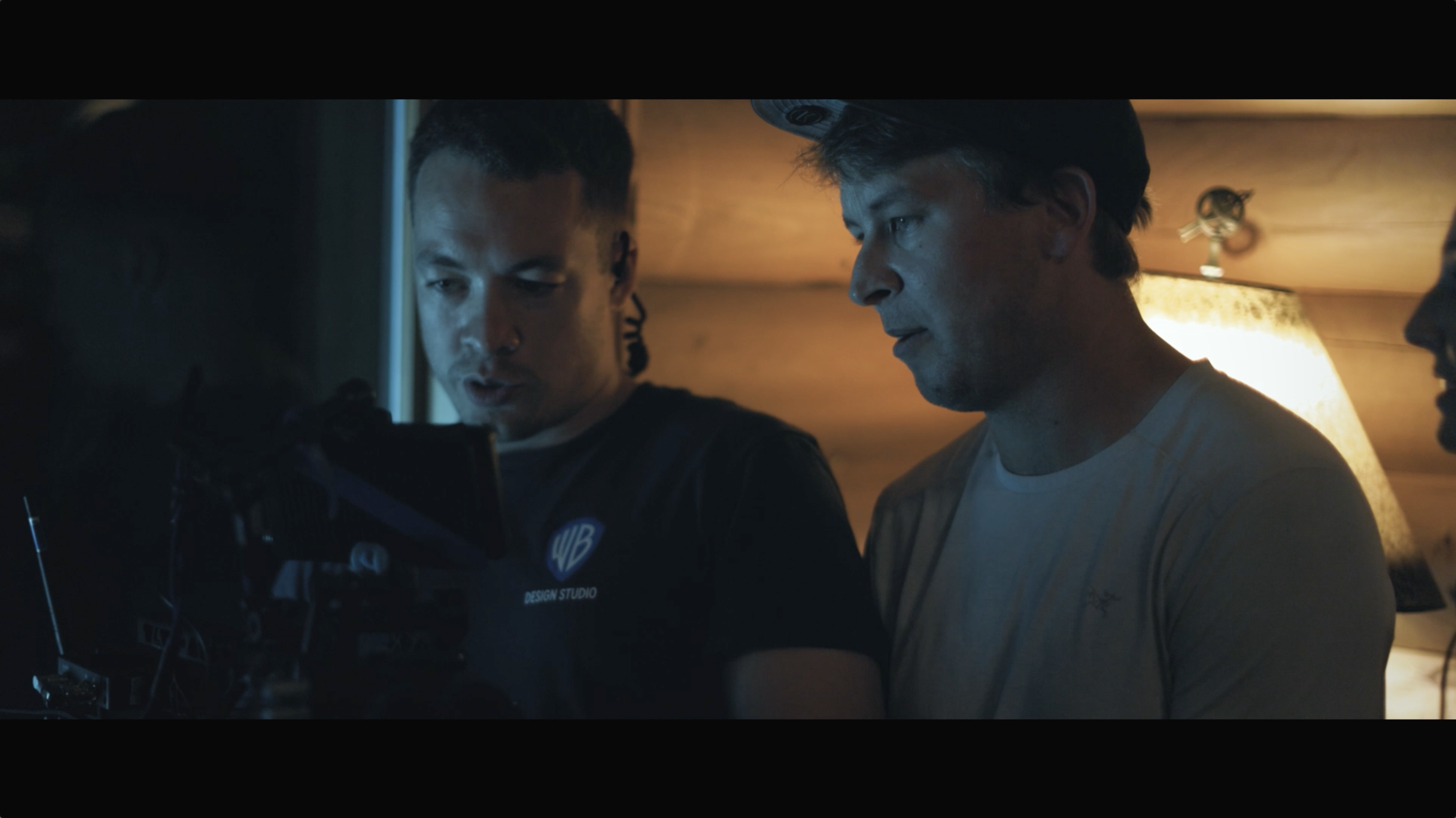 Two crew members review footage on a camera monitor, including CCS Photography (2010) alumnus Evan Butka, working as the director of photography on the set of SLAY, a horror film scheduled for release in 2025.