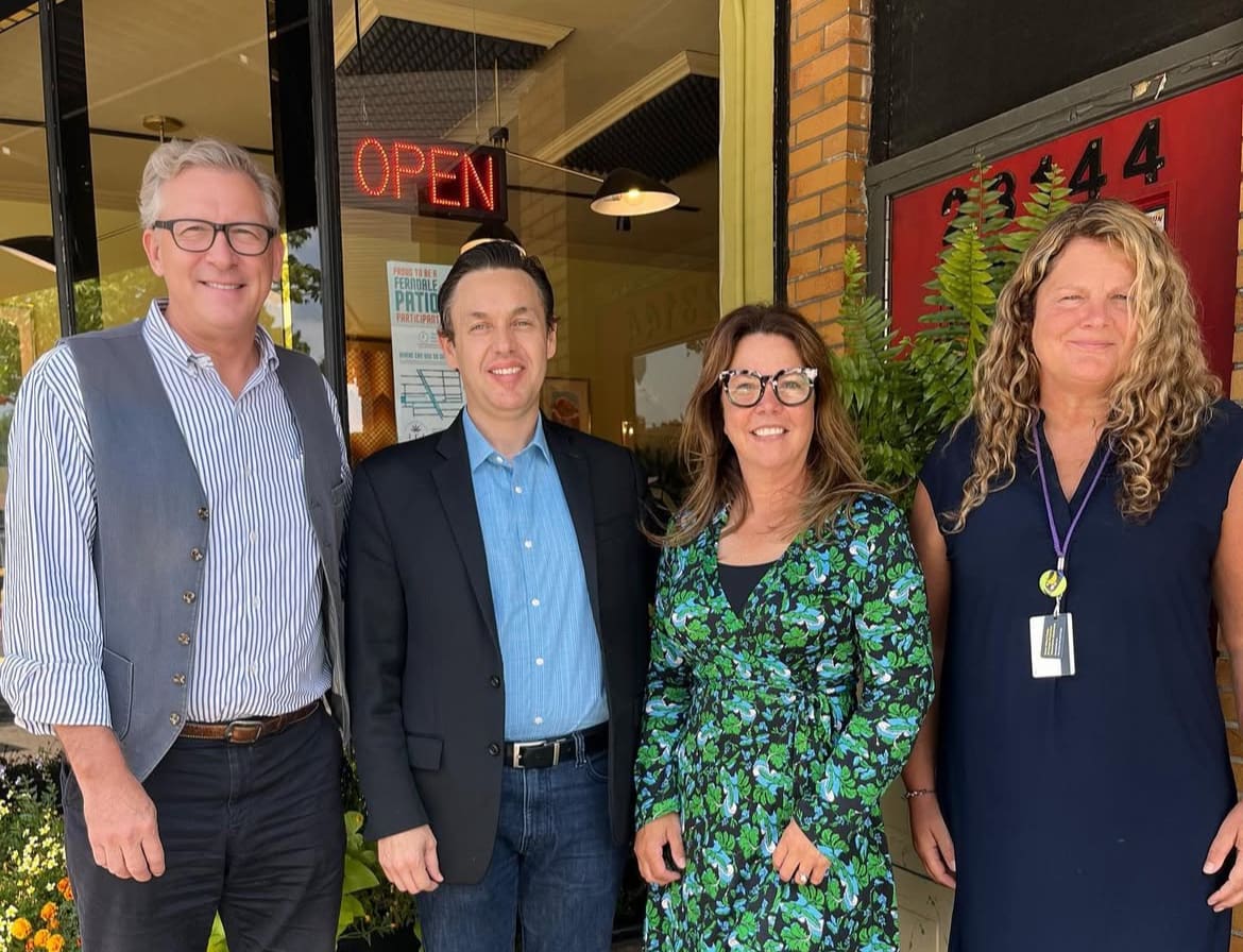 Tracy Muscat stands smiling with colleagues. 
