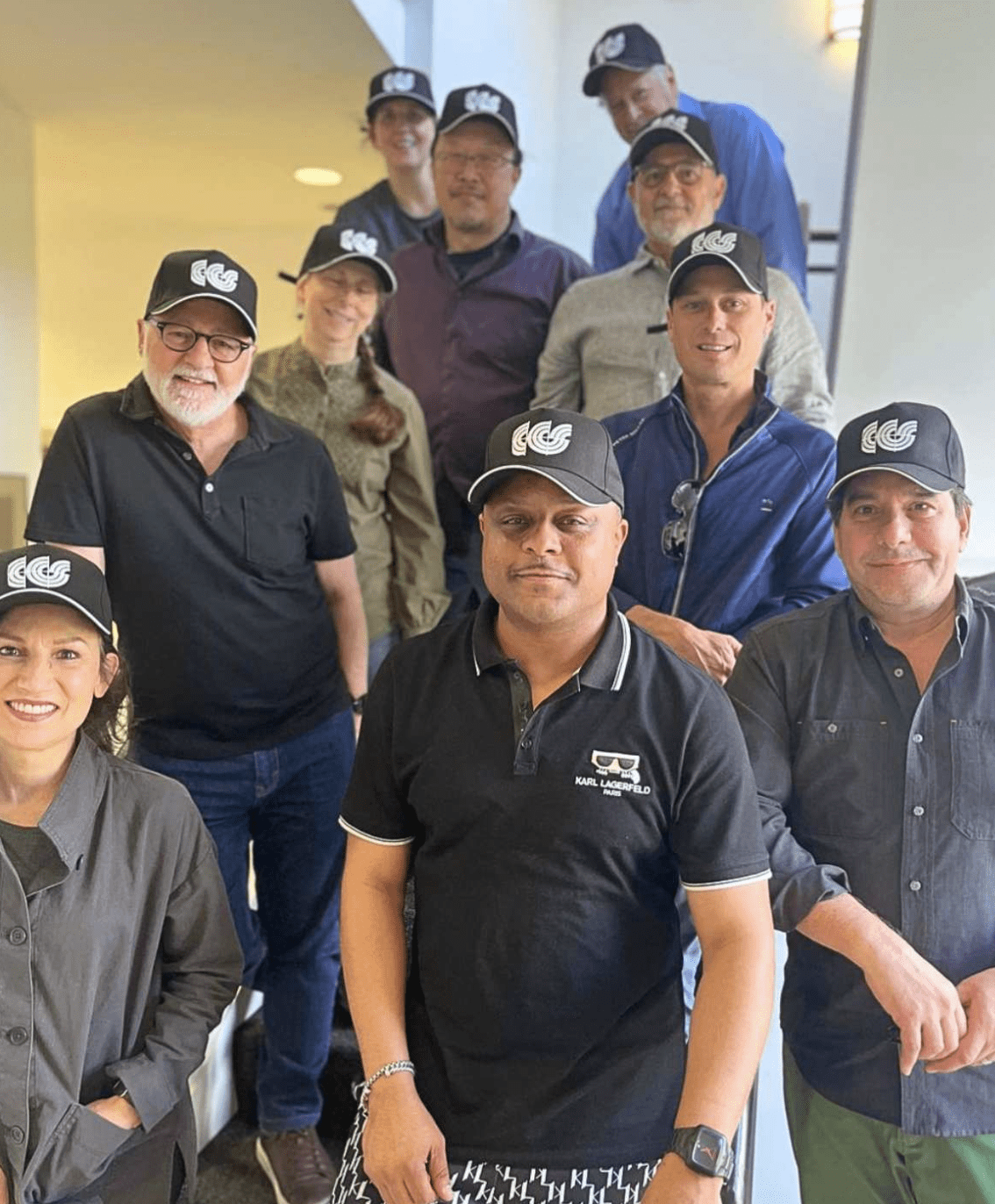 Group photo of ten members of the CCS Alumni Council wearing black CCS logo baseball caps.