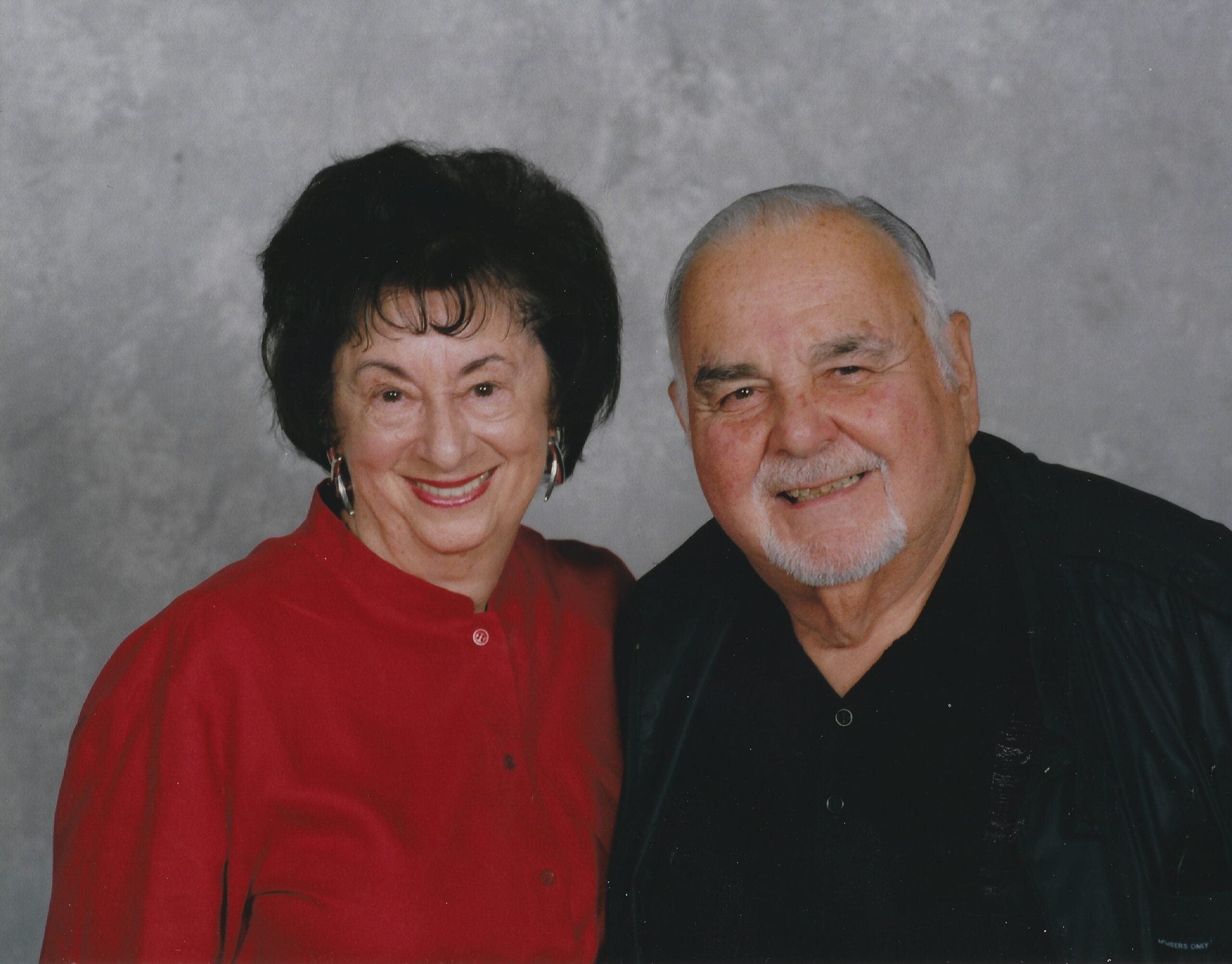 A framed, black-and-white newspaper article from 1981 titled "Colors are her energy." On the left, a photograph shows the artist Janice Charach standing next to her painting, "Indonesian Puppets," which is a vibrant, stylized depiction of three figures. The accompanying text details her art show and her painting style.
