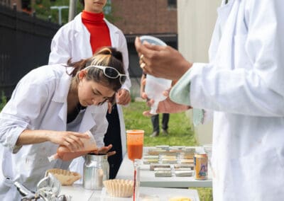 a group of students wearing white lab coats demonstrating their process for creating a bio-based sustainable spray paint