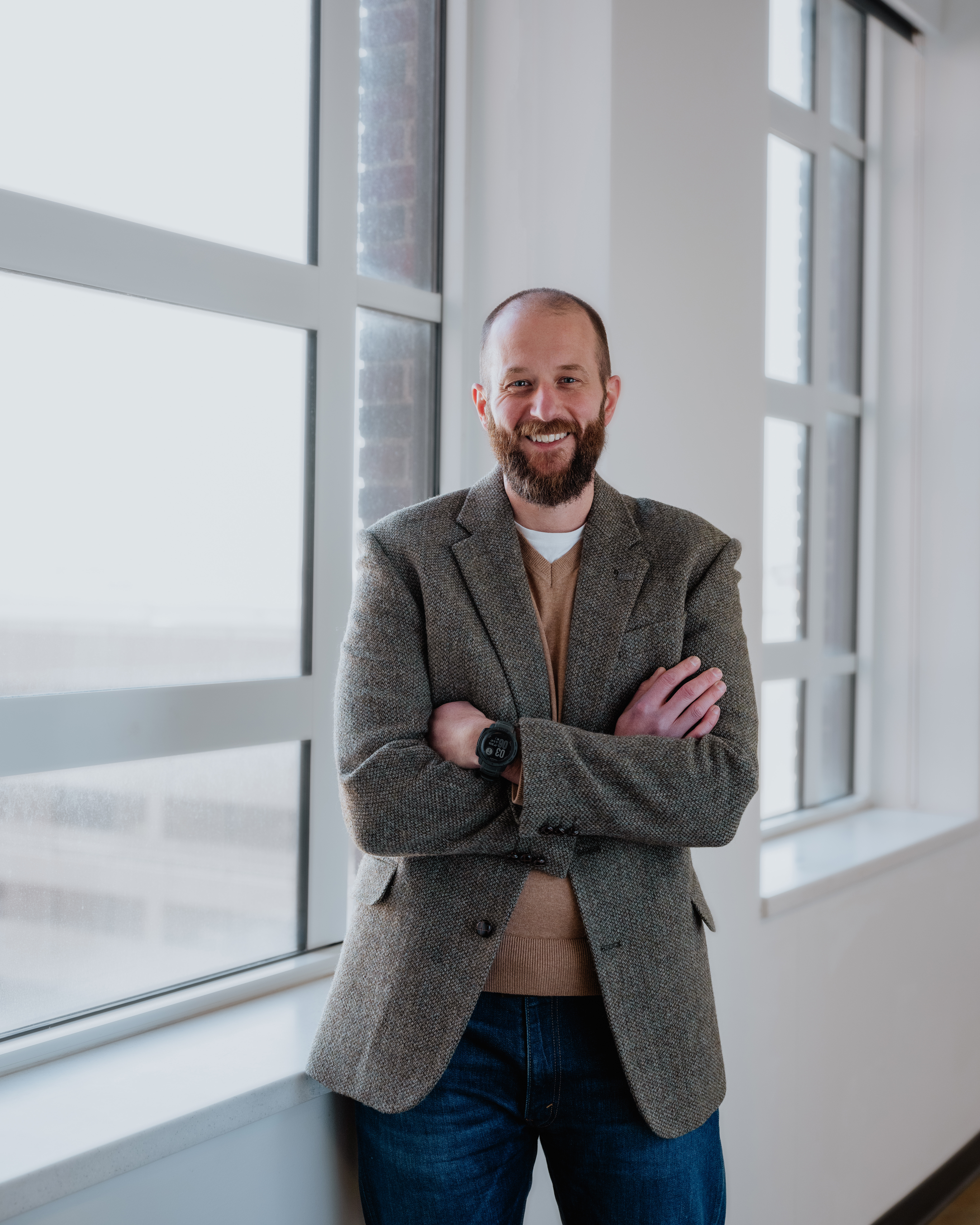 A professinal headshot of Assistant Vice President for Campus Life Dan Long standing arms folded, smiling.