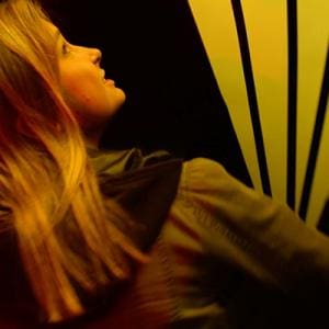 Entertainment Arts Digital Film. Photo of a woman in dramatic yellow lighting next to yellow stripes.