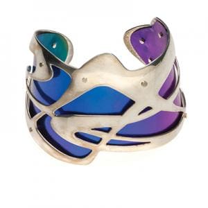 Metalsmithing & Jewelry Design. A silver cuff bracelet with purple and blue glass shapes in between the silver frame.