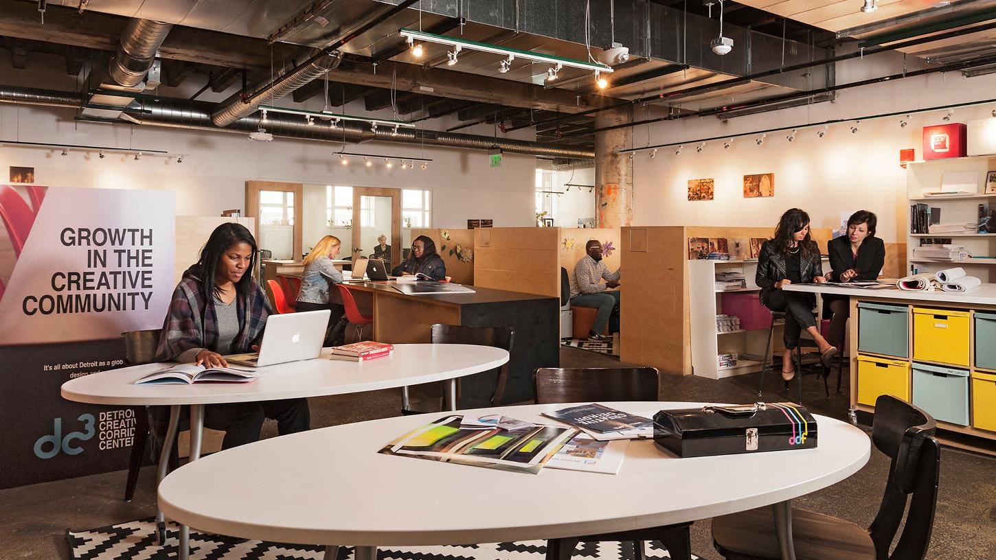 various people sitting at desks while working and talking at a community event