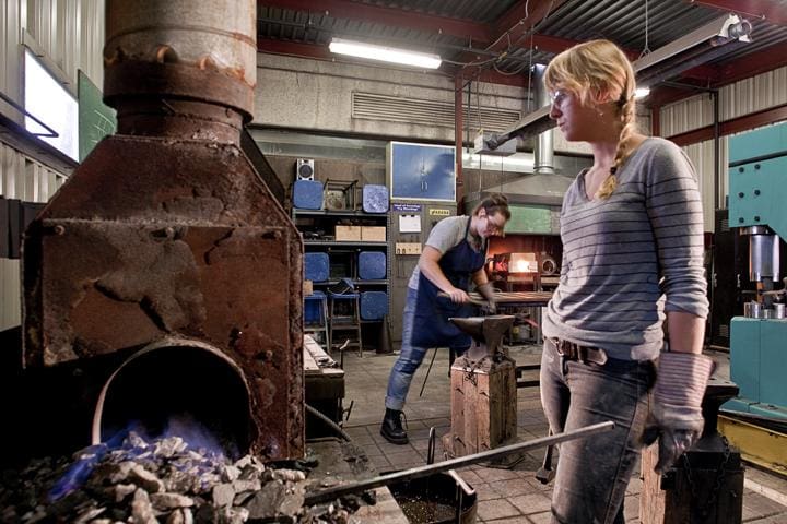 woman heating up metal at the blacksmith forge
