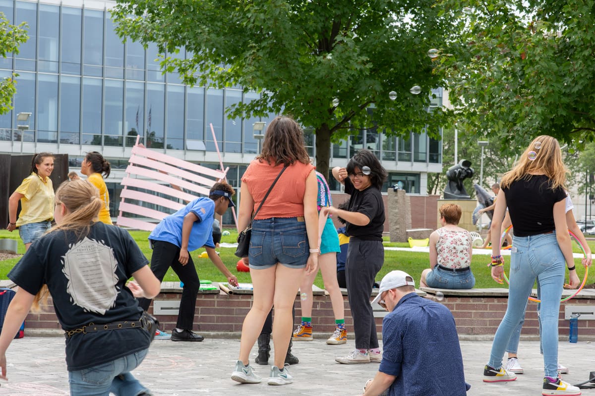 Group of students laughing and blowing bubbles together in the Ford Campus Sculpture Garden