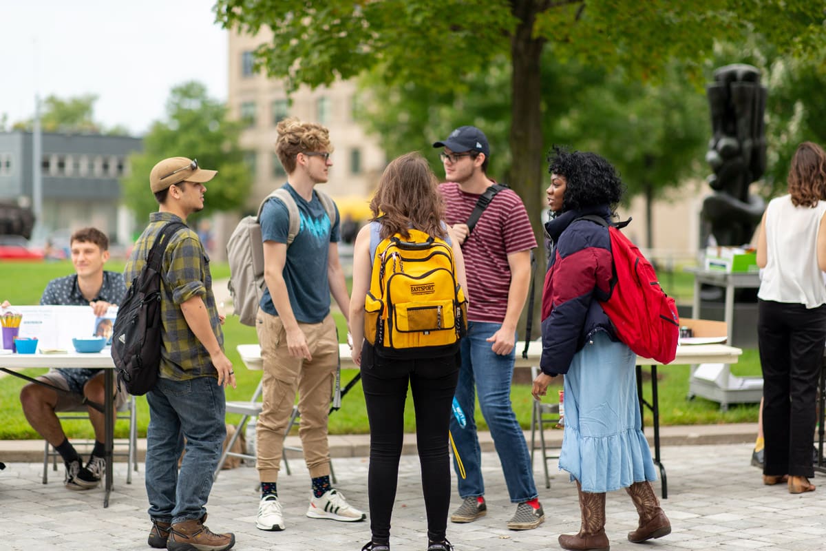 Photo of a group of students talking together in front of an outside club fair