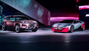 Two cars in a display room. The car on the left is dark pink with a black underside. The sportscar on the right is silver with a black underside and a red front and rear bumper