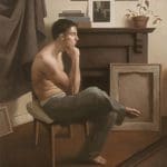 a shirtless man sitting in a chair with one leg over the other