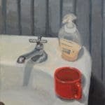 a red mug and bottle of soap on a bathroom sink