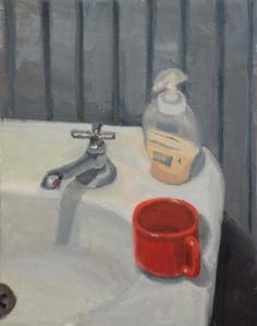 a red mug and bottle of soap on a bathroom sink