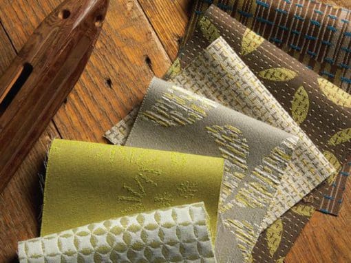 Various green and brown patterned fabric swatches on a hardwood table
