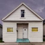 Photo of a white house with yellow curtains