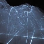 Large translucent grey holographic sculpture on a black backdrop