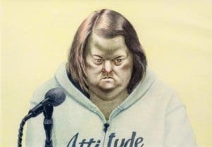 a person in a hoodie sitting in front of a microphone