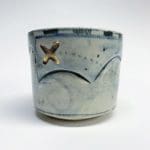 a golden x on a faded blue ceramic cup