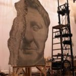 Sculpture consisting of a rough slab of granite with a portrait of a man sand-blasted on the side